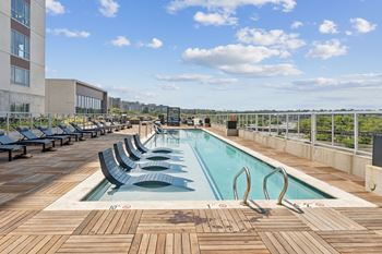 A large outdoor swimming pool with wooden decking and lounge chairs.